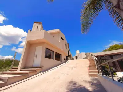 a white house with a palm tree in front of it at Complejo Costa Linda in Villa Carlos Paz