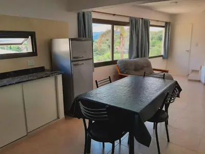 a kitchen with a table with chairs and a refrigerator at Complejo Costa Linda in Villa Carlos Paz