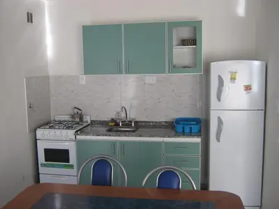 a kitchen with green cabinets and a white refrigerator at Cabañas Luna del Sur in Merlo