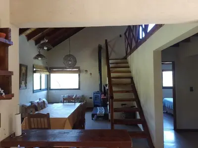 a living room with a staircase and a dining room at La Serranita in Santa Rosa de Calamuchita