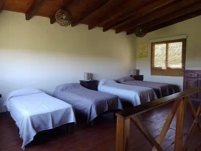 a room with three beds and a window at La Serranita in Santa Rosa de Calamuchita