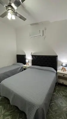 a room with two beds and two tables with lamps at Casa Familia Reynoso in Mina Clavero