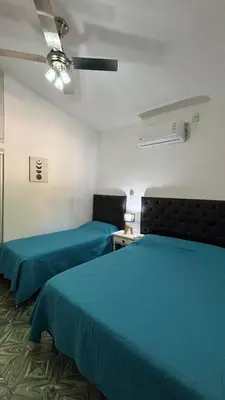 two beds in a room with blue sheets at Casa Familia Reynoso in Mina Clavero