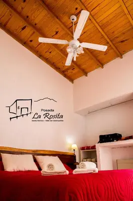 a bedroom with a red bed with a ceiling fan at Posada La Rosita in Santa Rosa de Calamuchita