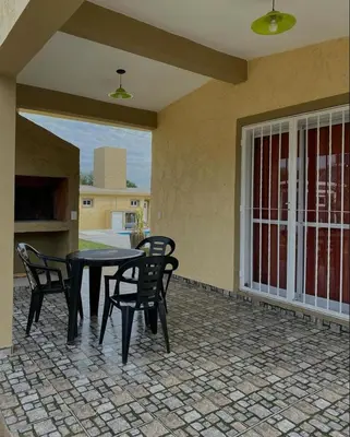 a patio with a table and chairs and a window at Cabañas Emilia in Mina Clavero