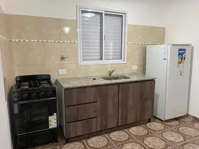 a kitchen with a stove and a sink and a refrigerator at Cabañas Emilia in Mina Clavero