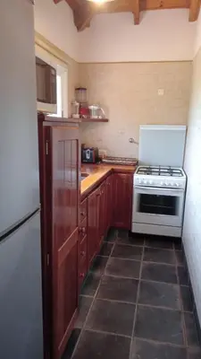a kitchen with wooden cabinets and a white stove top oven at Cabaña romántica en la sierra in Yacanto