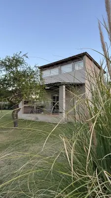 a house sitting on top of a grass field at La Calandria, Casa de campo in La Estancia