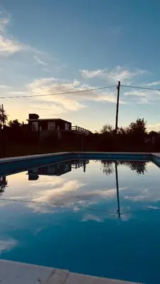 a pool of water with a house in the background at La Calandria, Casa de campo in La Estancia