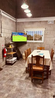 a room with a table with chairs and a television at La Calandria, Casa de campo in La Estancia