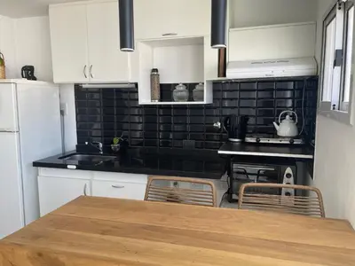 a kitchen with white cabinets and a black tile wall at Departamento con PILETA y gran balcón terraza con quincho y asador propio in Cordoba