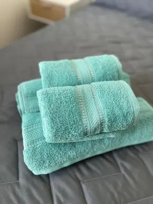 three green towels stacked on top of a bed at Departamento con PILETA y gran balcón terraza con quincho y asador propio in Cordoba
