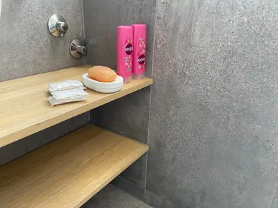 a bathroom with pink bottles on a wooden shelf at Departamento con PILETA y gran balcón terraza con quincho y asador propio in Cordoba