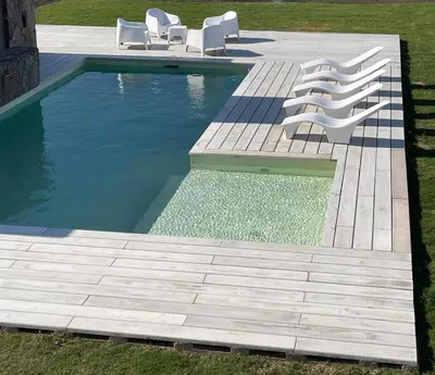 a swimming pool with white chairs next to a wooden deck at La Morada Almafuerte in Almafuerte
