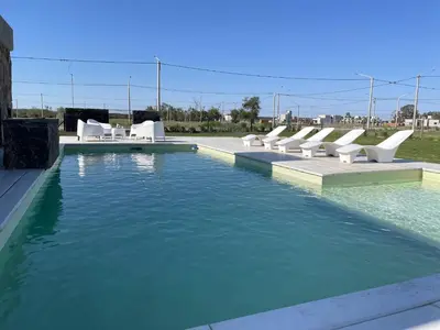 a swimming pool with white chairs and water at La Morada Almafuerte in Almafuerte