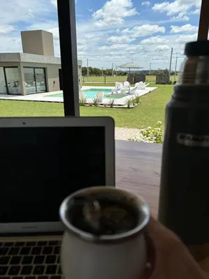 a person holding a cup of coffee next to a laptop at La Morada Almafuerte in Almafuerte