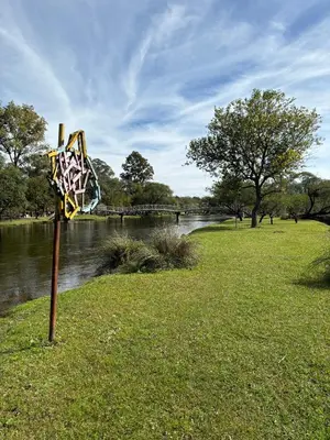 a sign in the grass next to a river at La Morada Almafuerte in Almafuerte