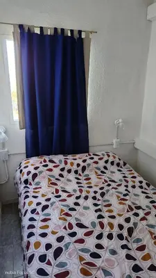 a bed in a bedroom with a blue curtain at lo de andres y marina in Arroyo de Los Patos
