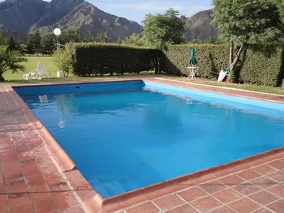 a large blue swimming pool with mountains in the background at Hotel Lujan in Luján