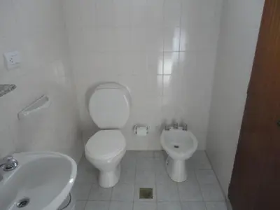a white bathroom with a toilet and a sink at Hotel Lujan in Luján