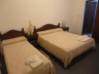 a hotel room with two beds and two lamps at Hotel Lujan in Luján