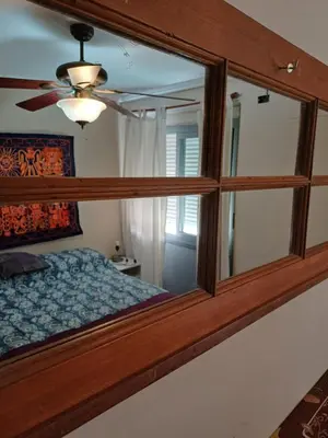 a mirror in a bedroom with a bed and a ceiling fan at Alto Villasol depto torre bastion in Cordoba