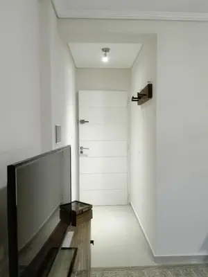 a hallway with white walls and a large television at Alto Villasol depto torre bastion in Cordoba