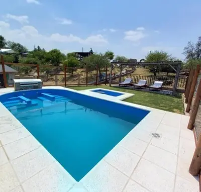 a large blue swimming pool with two lounges at Cabaña 3 in Bialet Massé