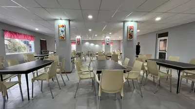 a dining room with tables and chairs and a man at Tata Inti Complejo Serrano in Merlo