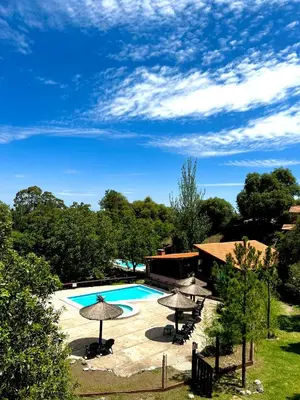 a large swimming pool with umbrellas and a building at Tata Inti Complejo Serrano in Merlo