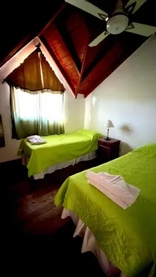 a bedroom with two green beds and a ceiling fan at Tata Inti Complejo Serrano in Merlo