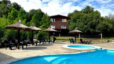 a pool with chairs and umbrellas next to a building at Tata Inti Complejo Serrano in Merlo