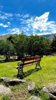 a park bench sitting in a field of grass at Tata Inti Complejo Serrano in Merlo