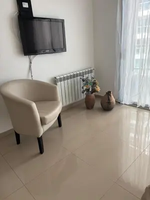 a living room with a chair and a tv on the wall at Departamento 6 piso con piscina, de 1 dormitorio in Río Cuarto