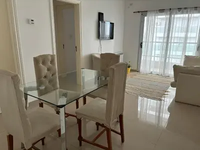 a glass dining room table with chairs and a television at Departamento 6 piso con piscina, de 1 dormitorio in Río Cuarto