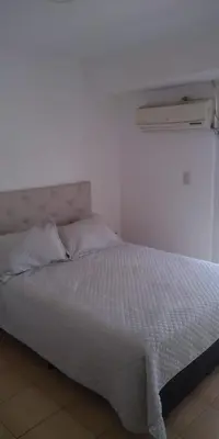 a white bed in a room with a white wall at Cálido departamento en CBA in Cordoba
