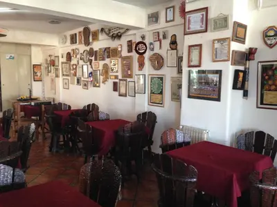 a dining room with red tables and pictures on the walls at Hotel Verde Sol in Villa Carlos Paz