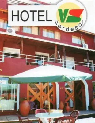 a table with an umbrella in front of a hotel at Hotel Verde Sol in Villa Carlos Paz