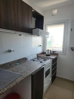 a kitchen with a white stove top oven next to a window at TORRE MAFALDA 15 Departamento nuevo con Pileta in Río Cuarto