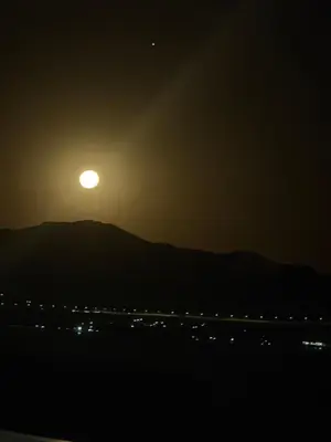 a sunset with the moon over a mountain and a highway at EL PALMAR in Villa Carlos Paz