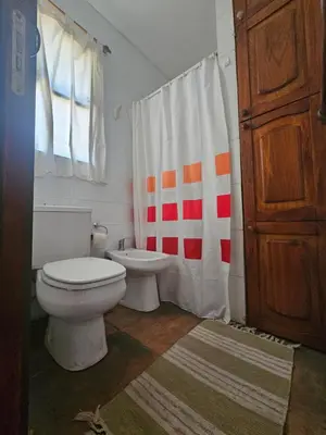 a bathroom with a toilet and a shower curtain at Nuestro Balcón a las Sierras in Merlo