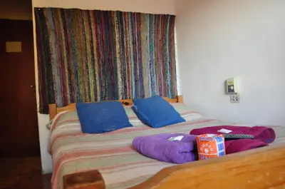 a bed with two blue pillows and a box on it at Hotel La Marina in Villa Carlos Paz