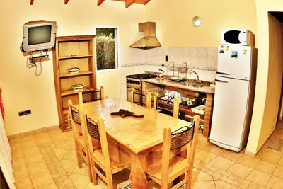 a kitchen with a wooden table and a refrigerator at Cabañas Amanecer en el Lago in Villa del Dique