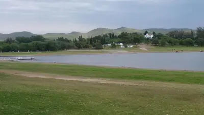 a large body of water with a house in the background at Cabañas Amanecer en el Lago in Villa del Dique