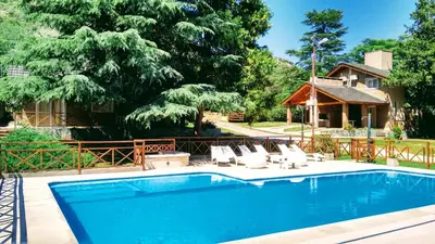 a swimming pool with chairs and a house at Cabañas Amanecer en el Lago in Villa del Dique