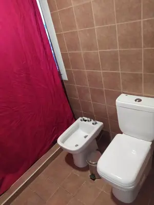 a bathroom with a toilet and a red shower curtain at Dto Costanera Antigua Cerveceria 3 dorm 2 cocheras 4 cuadras del centro in Cordoba