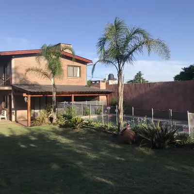 a house with two palm trees in a yard at Cabañas Brick House in Embalse