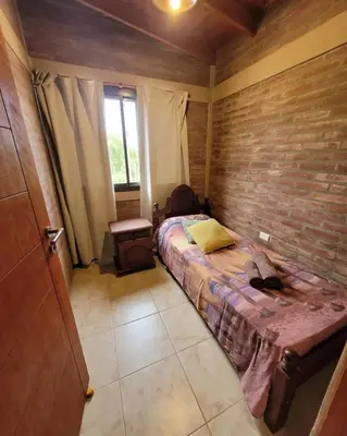 a bedroom with a bed and a brick wall at Cabañas Brick House in Embalse