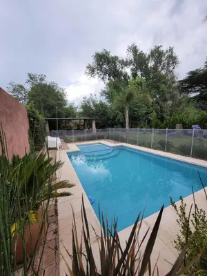 a swimming pool with blue water in a yard at Cabañas Brick House in Embalse