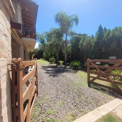 a wooden fence next to a house with a tree at Cabañas Brick House in Embalse